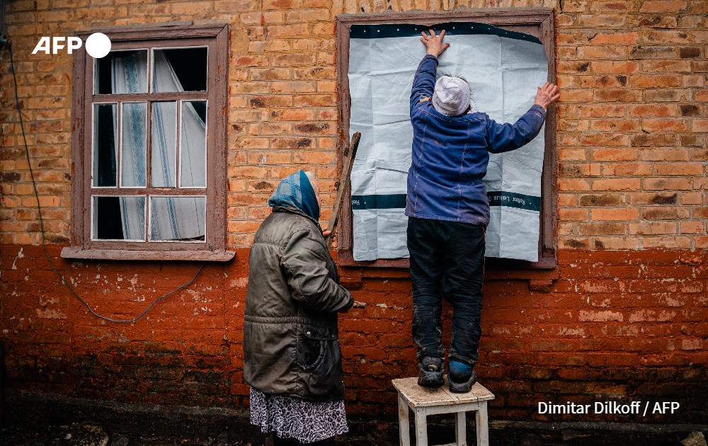 Eldery women placard a sheet over a windows after shelling in Ukraine