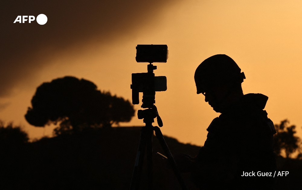 Member of the media stands behind his camera