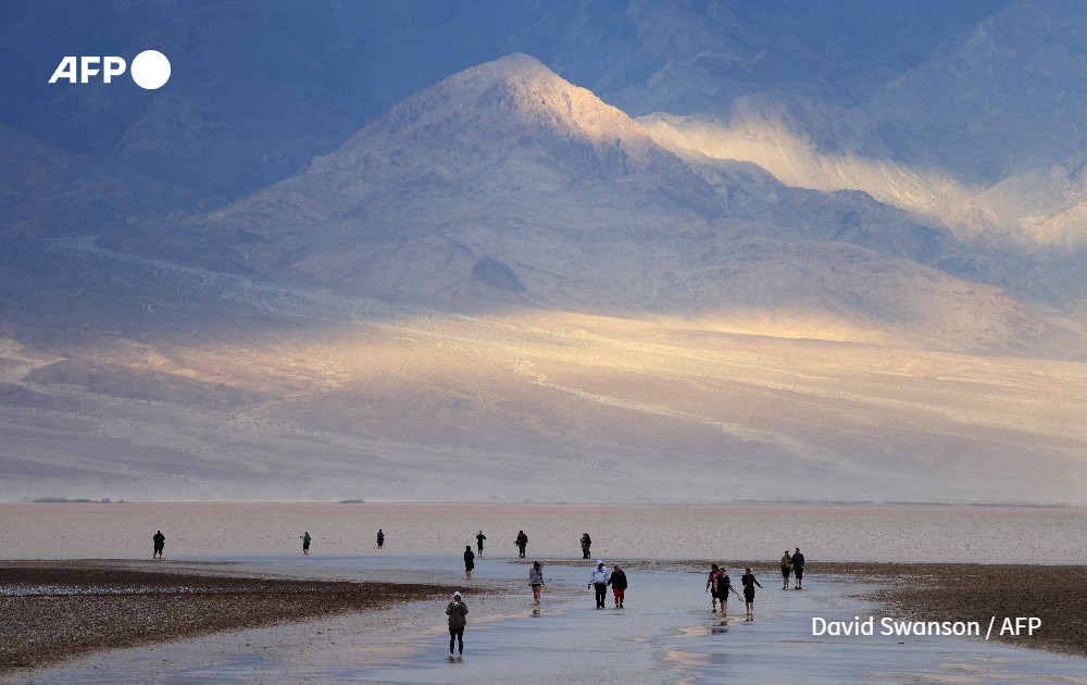 Tourists walk in water as they visit Badwater Basin