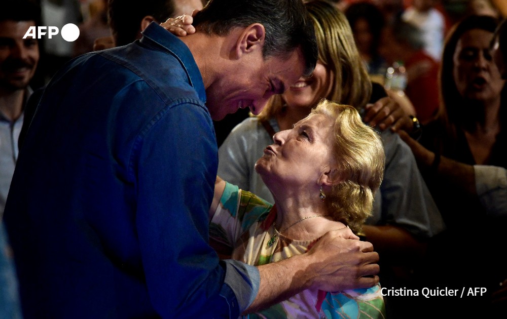 Spanish Prime Minister Pedro Sanchez is kissed by a woman during a campaign rally.